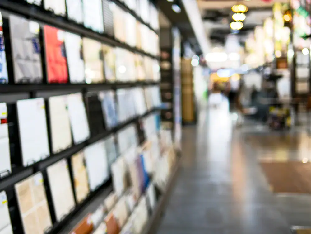 Vaag beeld van 'n winkelgang met rye rakke wat boeke en tydskrifte vertoon, met 'n onskerp loopvlak wat in die verte strek—ideale inspirasie vir vloerinstallasie in Wake County, NC en Horry County, SC.