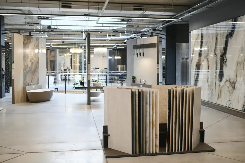 Modern showroom featuring large marble and stone tiles, a freestanding bathtub, wall samples, and contemporary fixtures under industrial-style lighting—serving SC, NC and Horry County residents seeking expert flooring installation.